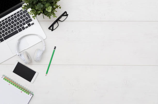 Office desk table with laptop, smartphone and supplies. Flat lay with copy space on white wooden background