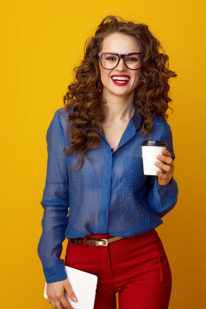 istock woman on yellow background with coffee cup and tablet PC 936428290