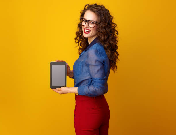 istock woman against yellow background showing tablet PC blank screen 936428794