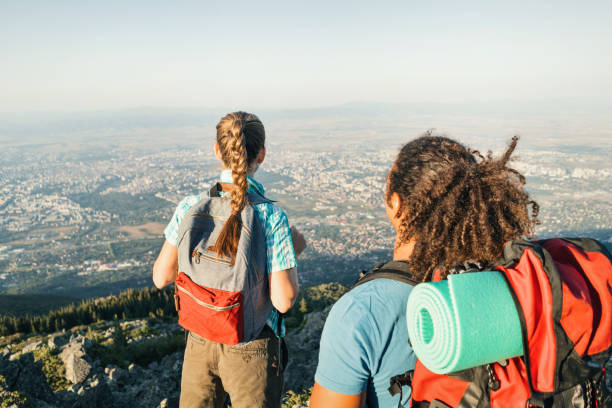 istock Couple hikers standing on the mountain peak and looking at the valley 936431482