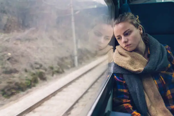 Young unhappy woman traveling by train and starring out of the window
