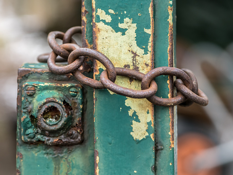 Old rusty iron chain wrapped around a green garden door, Austria
