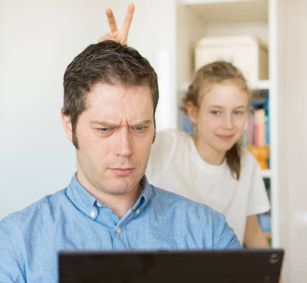 그는 태블릿 pc에 채팅 하는 동안 그녀의 아버지를 방해 하는 작은 소녀. - inconvenience meeting business distracted 뉴스 사진 이미지