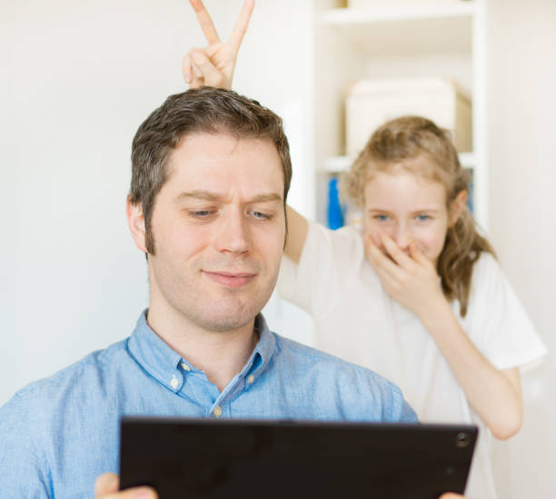 little girl disturbing her dad while he is chatting on tablet pc. - inconvenience meeting business distracted imagens e fotografias de stock