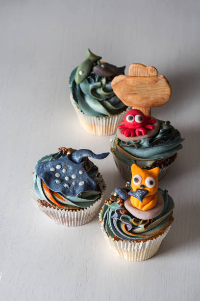 istock Capcake with animals from mastic and marzipan cat, fish and crab. Decor cake. Dark background. 936434222