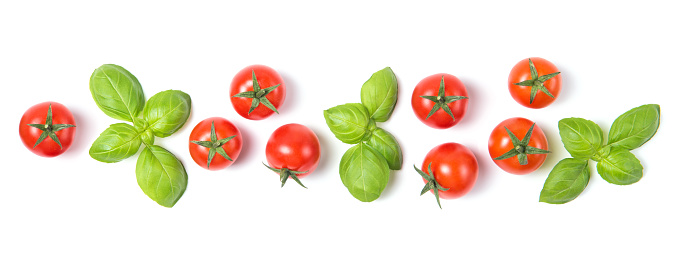 Beautiful border made of fresh red cherry tomatoes with basil leaves, isolated on white background, vegetable pattern, top view