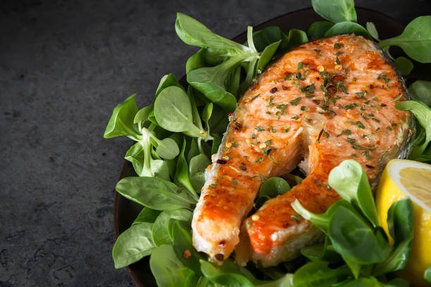 istock Grilled salmon steak with lemon, and spices. Cooked fresh fish. Restaurant menu. Dark background. 936435828