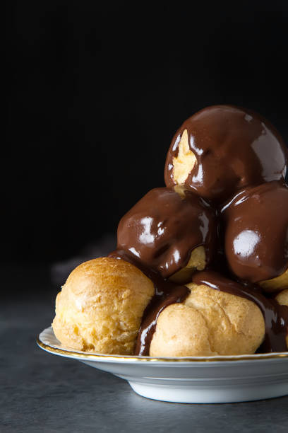 Profiteroles with cream and chocolate sause. Dark background
