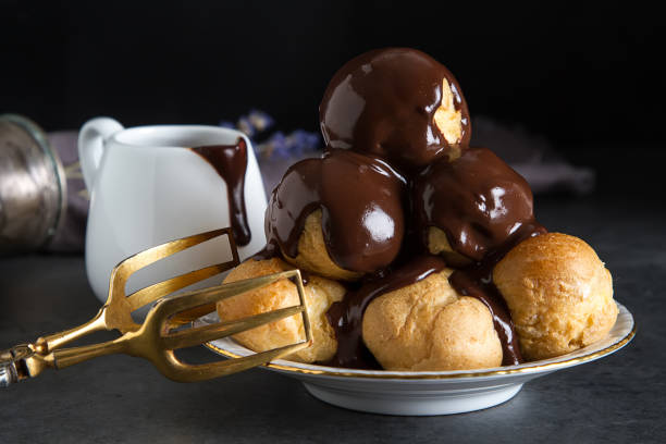 Profiteroles with cream and chocolate sause. Dark background. Profiteroles with cream and chocolate sause. Dark background choux pastry photos stock pictures, royalty-free photos & images