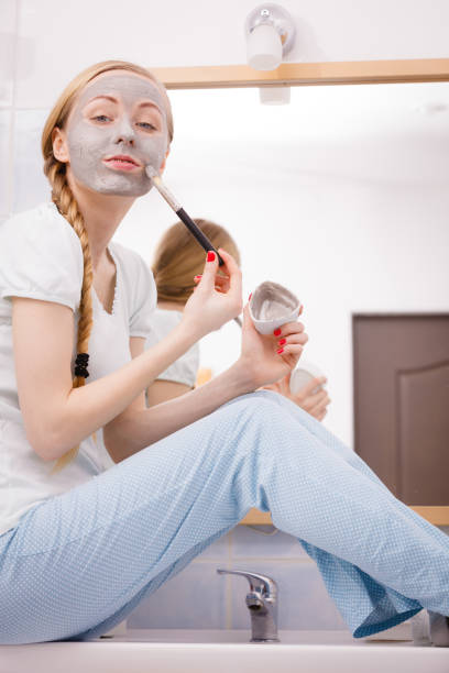 istock Woman applying with brush clay mud mask to her face 936436786