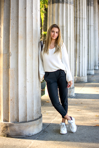 Girl leaning against pillar.