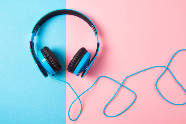 Minimalist bright composition of blue headphones on vibrant yellow background.