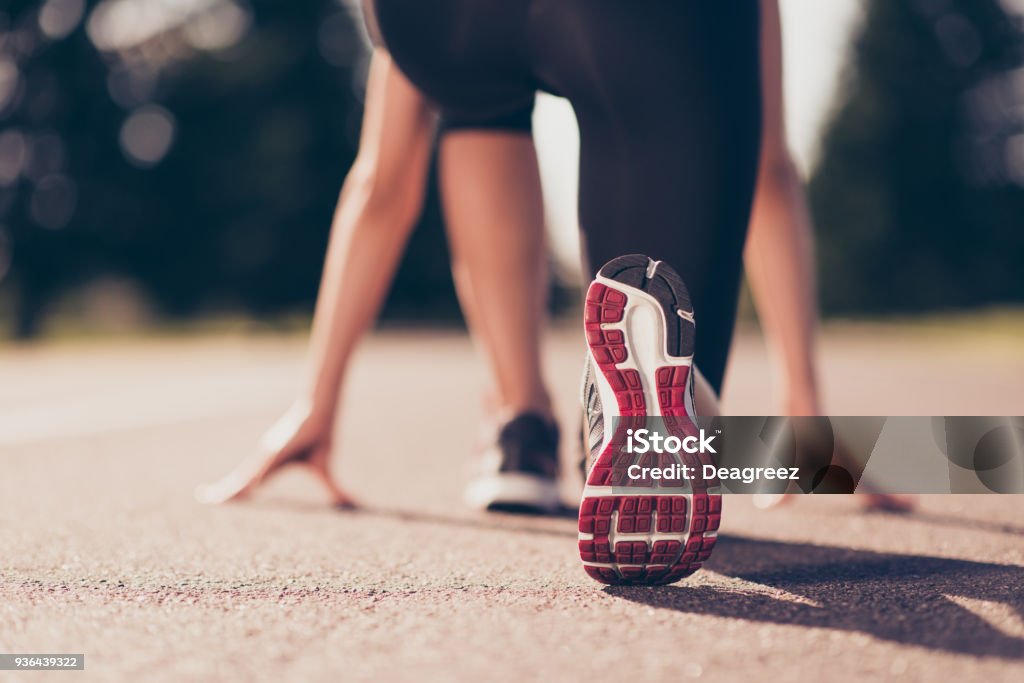 Prêt à partir ! Gros plan photo recadrée faible angle de chaussure de l’athlète féminine sur la ligne de départ d’une piste de stade, préparation pour une course. Journée de printemps ensoleillée - Photo de Courir libre de droits