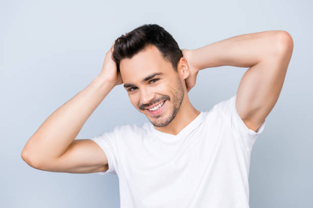 istock Confident smiling handsome young man in white t shirt. standing on the pure background, fixing his perfect hairstyle. So hot and attractive, harsh and fashionable 936439708