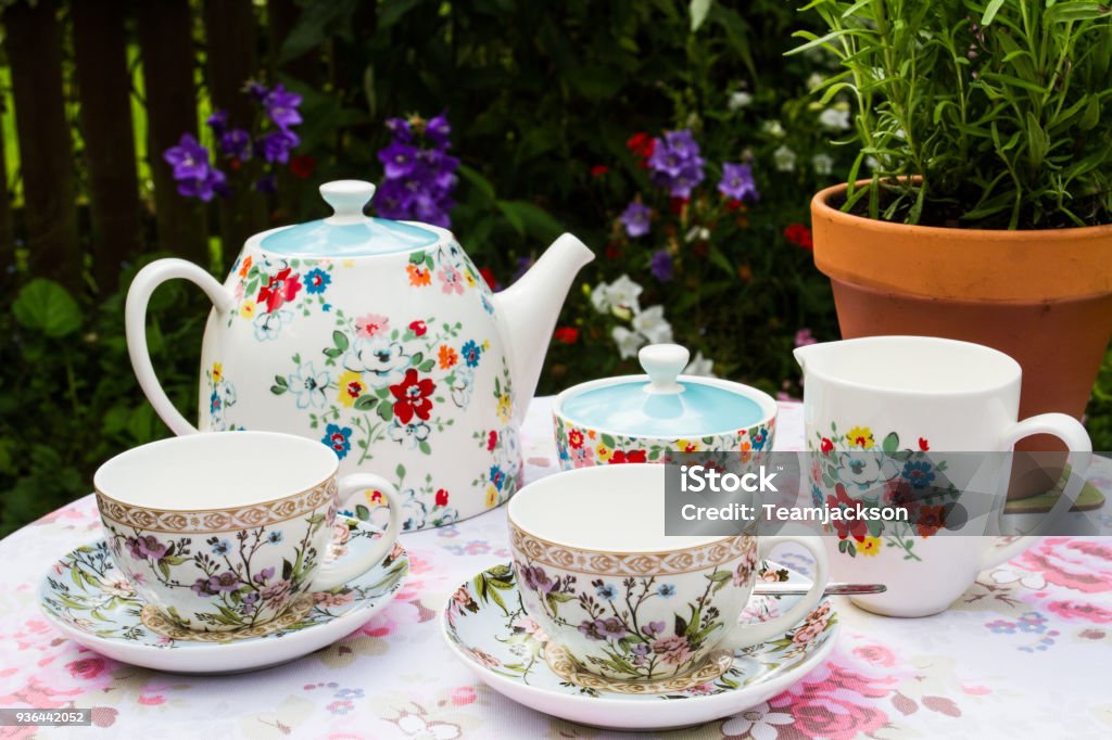 Floral Tea Service On A Picnic Table A pretty, floral tea service including teapot, cup and saucers a nd a milk jug in readiness for an afternoon tea in an English country garden. Afternoon Tea Stock Photo