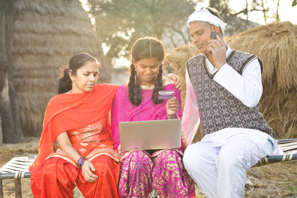 Indian family with laptop and credit card on village bed Parents with daughter shopping online using credit card and laptop on village bed bed of hay stock pictures, royalty-free photos & images