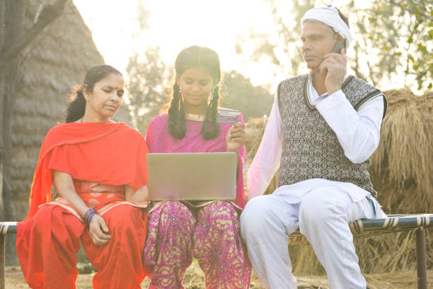 Indian family with laptop and credit card on village bed Parents with daughter shopping online using credit card and laptop on village bed bed of hay stock pictures, royalty-free photos & images