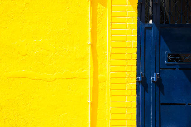 istock Yellow wall and blue metal door background 936444434