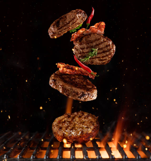 pieces of minced meal for hamburgers flying above grill - barbecue grill barbecue burger hamburger imagens e fotografias de stock