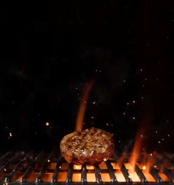 Photo of Piece of minced meal for hamburger placed on grill grid.