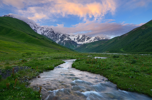 River in the mountains. Colorful sunset with beautiful clouds. Summer landscape. Main Caucasian ridge. Zemo Svaneti, Georgia