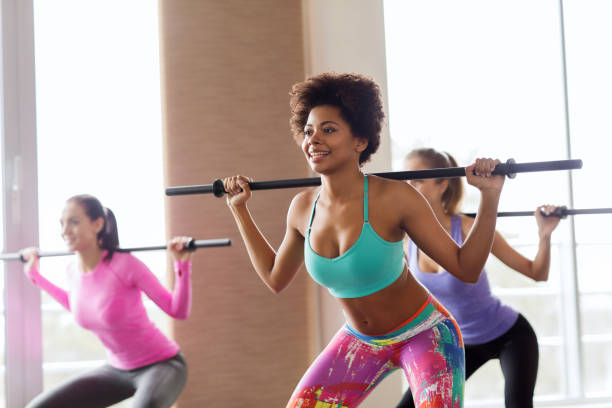 istock group of people exercising with bars in gym 936449270