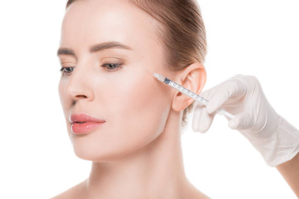 istock Beautician hands doing injection in woman cheek isolated on white 936456336