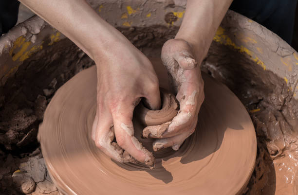 istock hands of a potter, creating an earthen jar on the circle 936470164