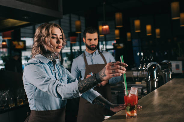 istock tattooed bartender putting plastic straws in glass with alcohol drink at bar 936478002