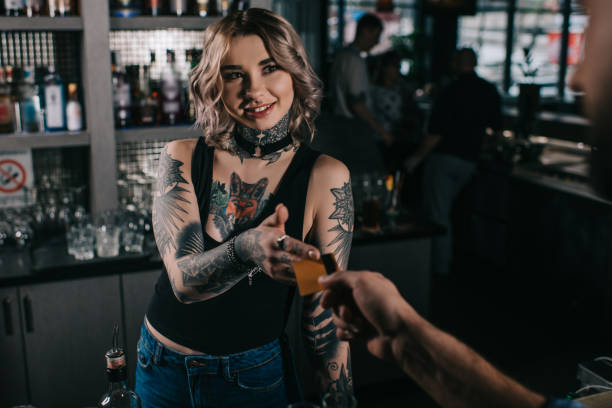 istock visitor giving credit card to tattooed bartender in bar 936478670