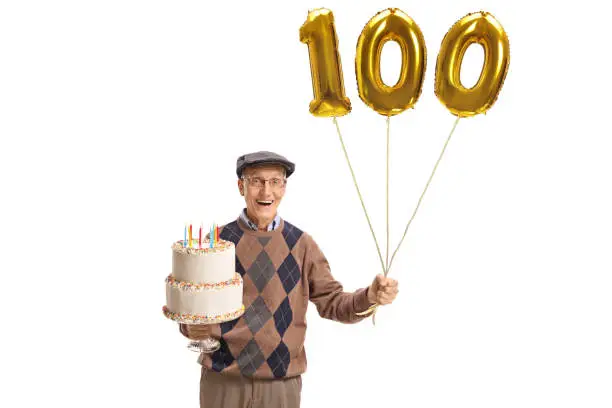Happy senior with a birthday cake and a number hundred balloon isolated on white background