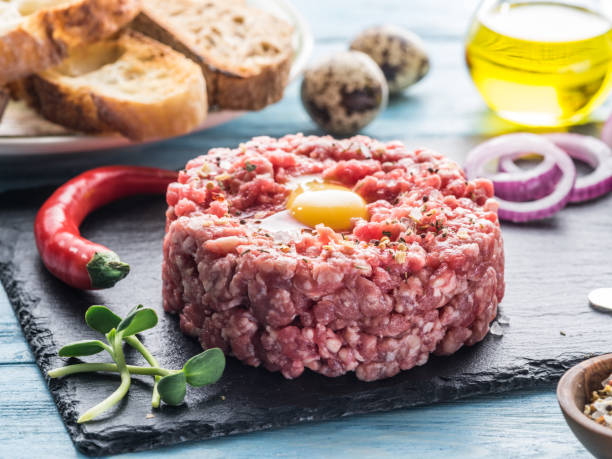 istock Steak tartare served with raw quail egg yolk, chilly pepper and bread. 936487736