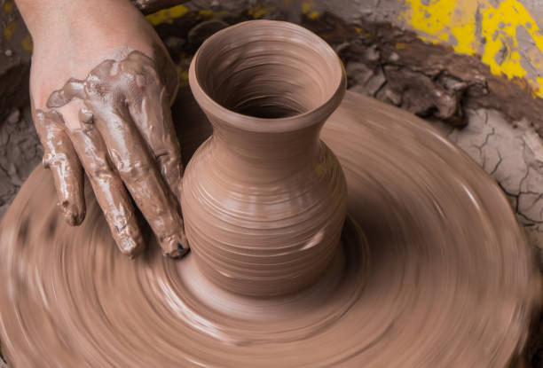 istock hands of a potter, creating an earthen jar on the circle 936489104