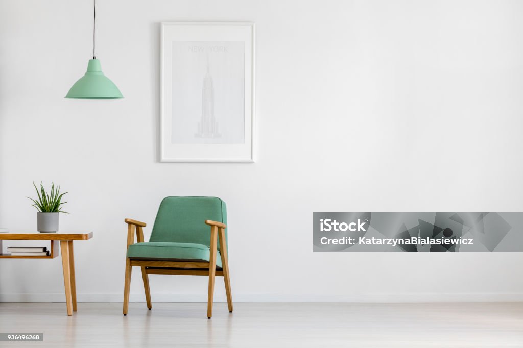 Retro armchair in bright interior Retro concept mint pastel armchair, wooden table and framed poster in a bright minimalist interior with copy space Sparse Stock Photo