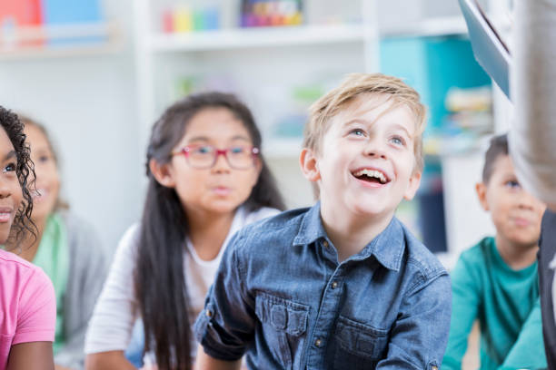 istock Happy schoolchildren enjoying story time 936496668