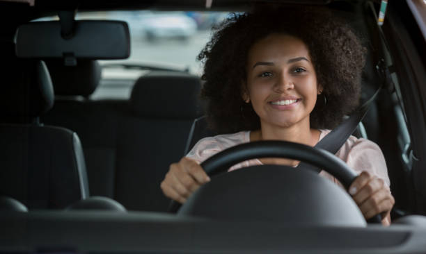 portrait of a happy black woman driving a car - car test drive car rental women imagens e fotografias de stock