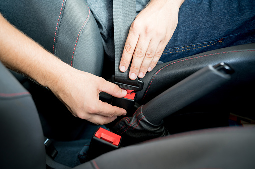 Close-up on a man fastening her seatbelt in a car â safety concepts