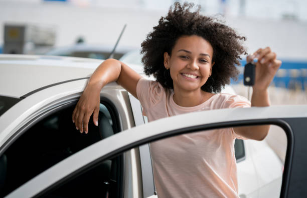 woman at the dealership holding keys to her new car - car test drive car rental women imagens e fotografias de stock