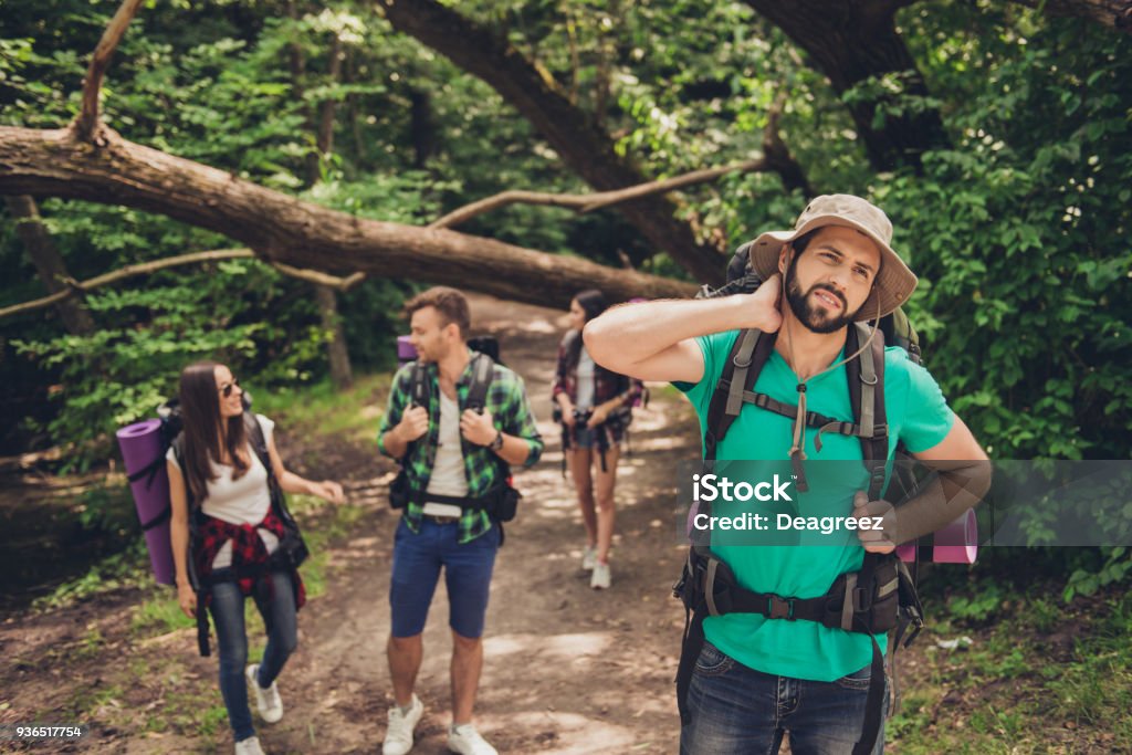 Hard, difficult, tiring and exhausting expedition of four friends in wild forest in trail. Guy is struggling of a neck pain, massaging it Mosquito Stock Photo