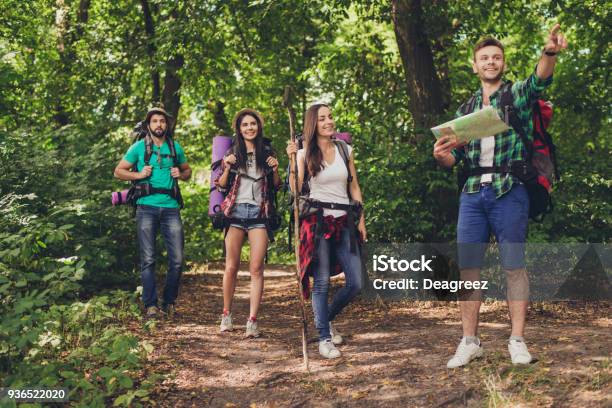 Trekking Camping And Wild Life Concept Four Best Friends Are Hiking In The Spring Woods The Guy Is Showing The Direction Lady Is Checking It On A Map All Are Excited And Anxious Stock Photo - Download Image Now