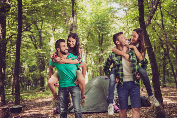 istock So fun together! Two lovely couples, nice forest view. Guys are piggybacking their girlfriends, so happy, smiling 936526066