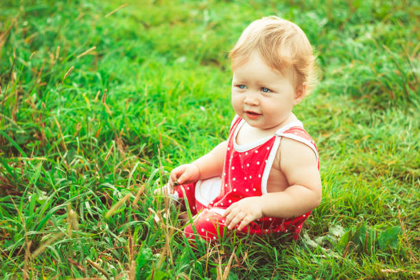 The child is sitting on the grass