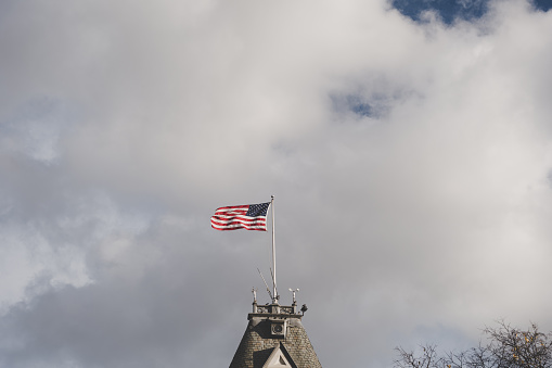 A vertical shot of a clocktower with the American flag on the top of the roof
