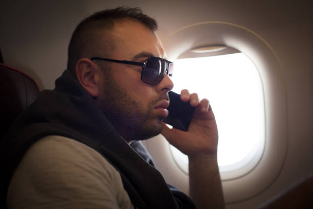 istock Young man talking on phone in airplane. Close up image. 936531676