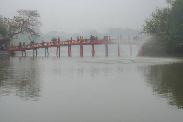 Hanoi, Vietnam: Febrary 23rd - People crossing the red foot bridge to visit the Ngoc Son Temple on a rainy day.