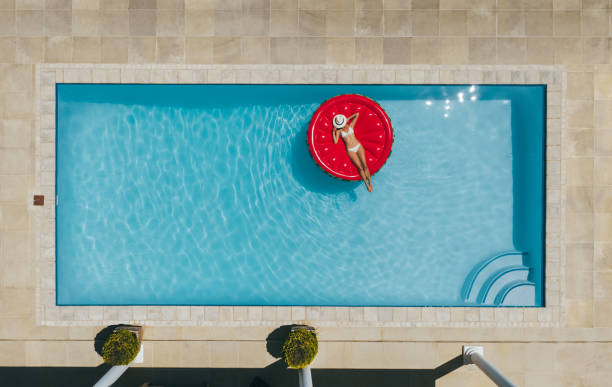 女性がプールで膨脹可能なマットレスの上で日光浴します。 - floating on water women swimming pool water ストックフォトと画像
