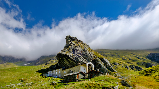 Sanctuary of San Besso, built with a side wall adjacent to the monolithic rock of Mount Fautenio. It is located in Valle Soana, a valley on the southern slope of the Gran Paradiso massif. Gran Paradiso National Park, Piedmont, Italy