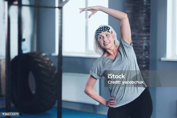 Cheerful Mature Lady Stretching During Training Session Stock Photo - Download Image Now