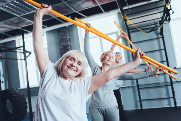 istock Cheerful women with stick doing side bending exercise at gym 936573428
