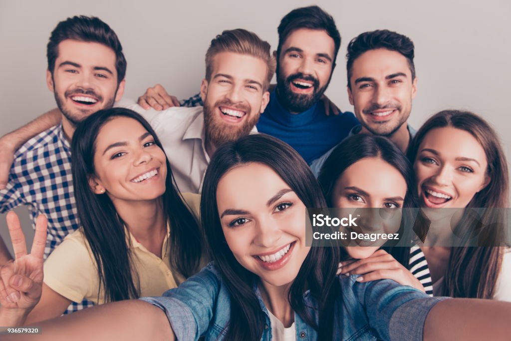 Brinde! Humor funky. Perto de selfie do amigo animado um oito, tomada pela menina morena. Jovens desfrutar de sua companhia, sorriam, divirtam-se - Foto de stock de Grupo de Pessoas royalty-free